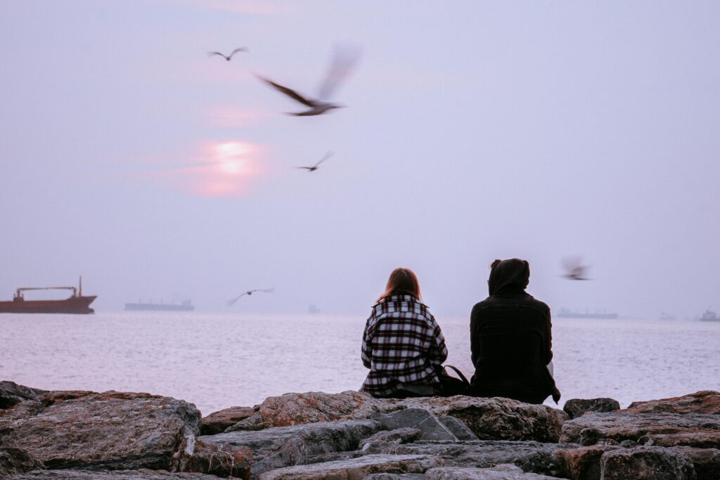 Couple Sitting on Rocks by the Sea